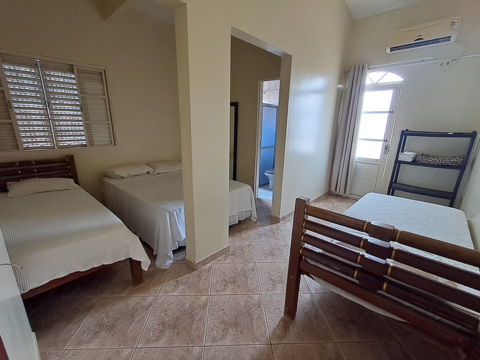 Quarto amplo com quatro camas, janela e ar-condicionado